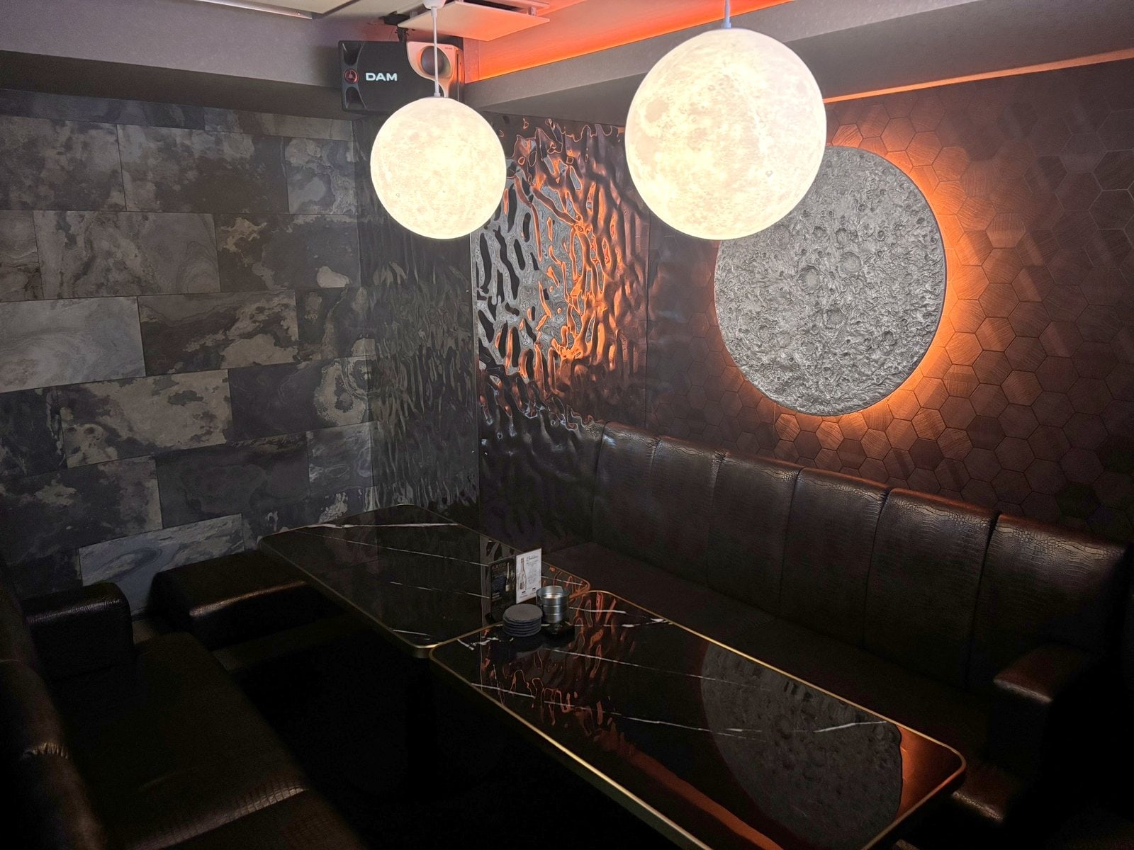 LUNE 六本木 6F VIP 1 — 背光月球壁飾、兩盞月球吊燈、黑色皮革沙發與大理石桌